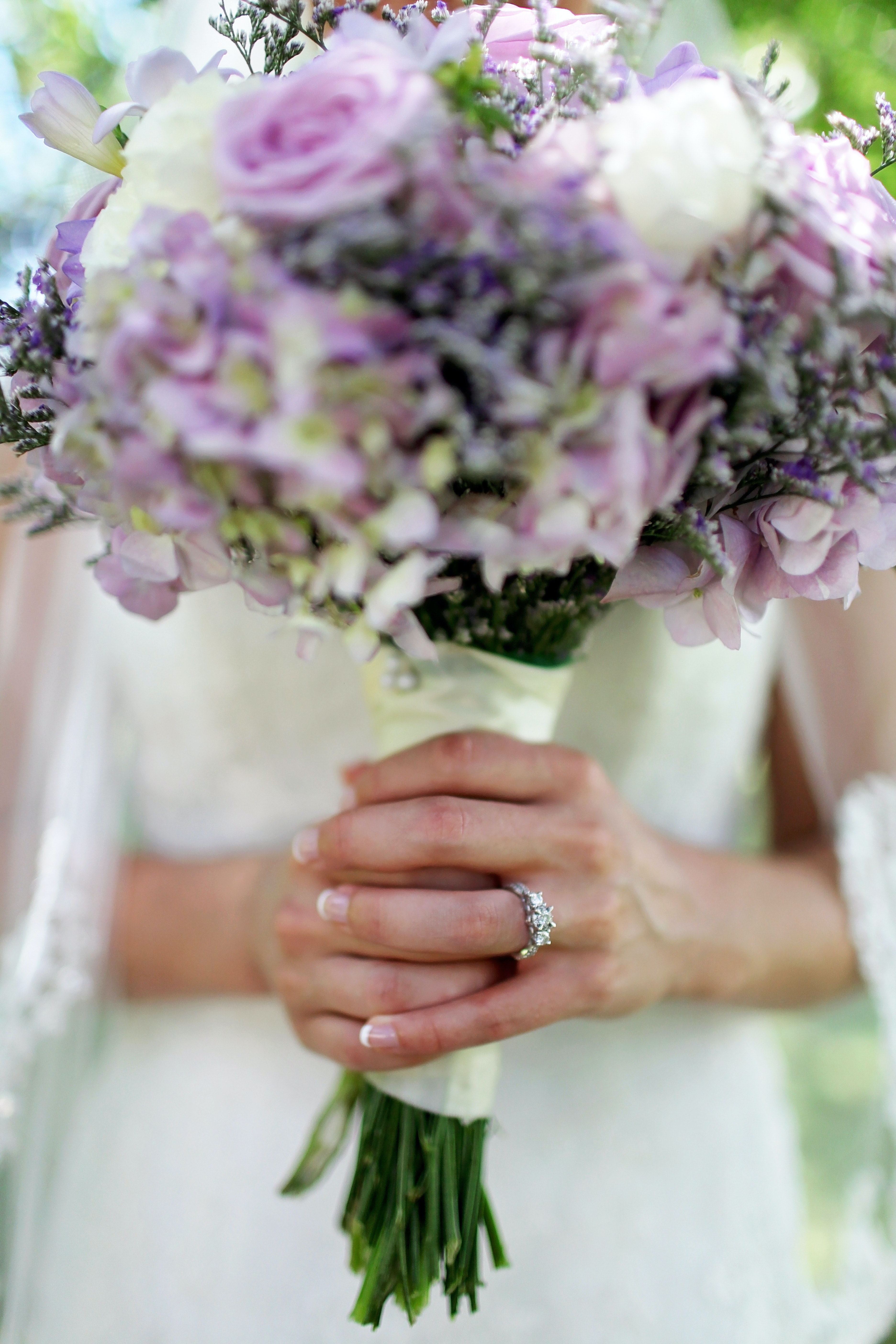 bride with Three Stone diamond ring holding boqut 