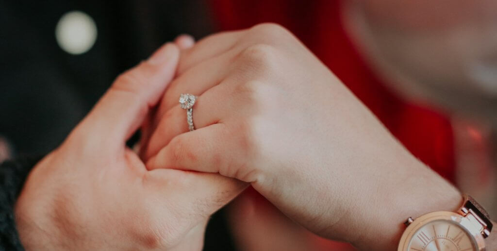 guy placing engagement ring on the correct left-hand ring finger